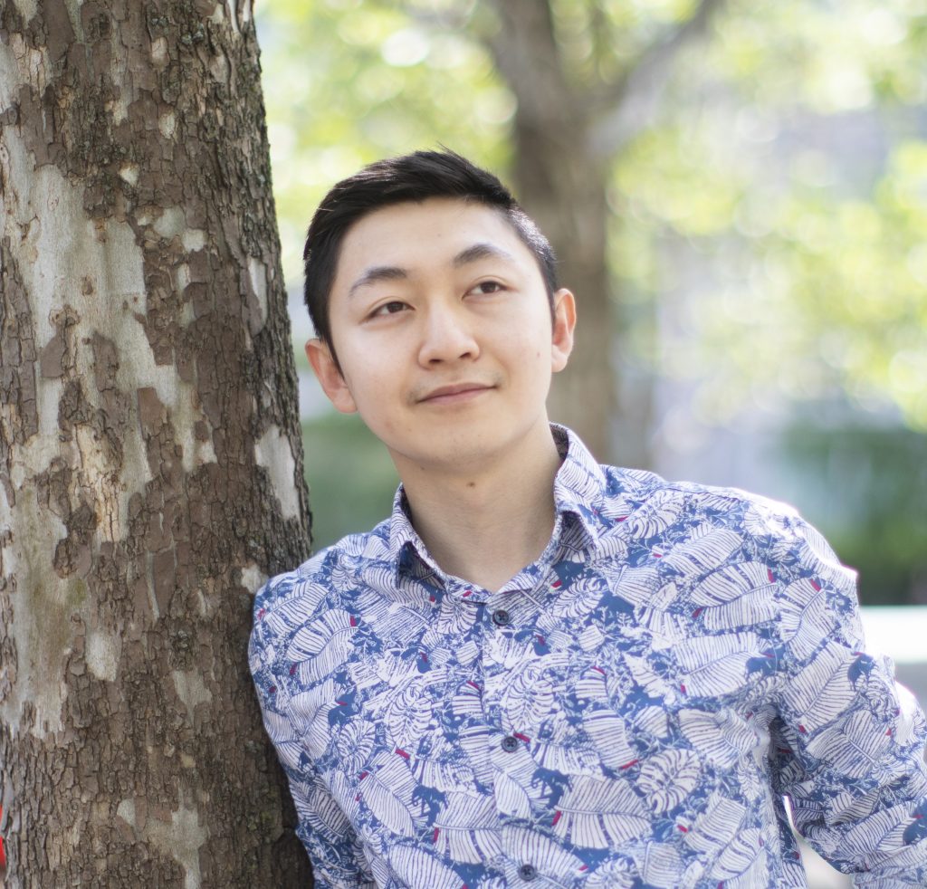 a square photo of Alex Lu, a smiling man with short hair and a blue dress shirt. Alex Lu, third-year PhD student in the department of computer science at the Faculty of Arts & Science. photographed in downtown Toronto, June 4, 2020. (Photograph by Nick Iwanyshyn)