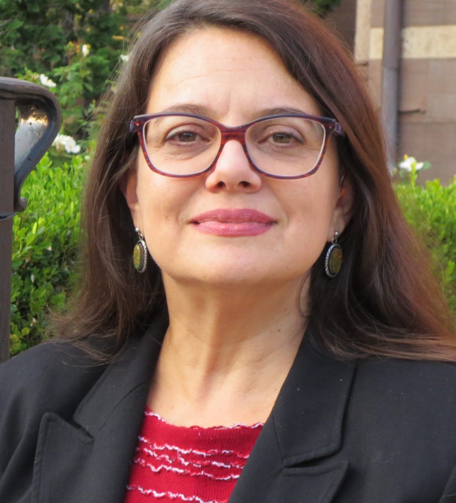 photo of Teresa Blankmeyer Burke, a woman with long brown hair in red glasses and a black blazer