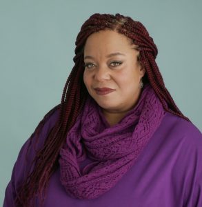 photo of Erin Sanders-Sigmon, a Black woman with red braids in a purple outfit