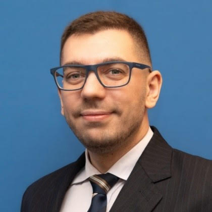 photo of Santiago Krsul, a man with very short brown hair and black glasses, wearing a suit and tie